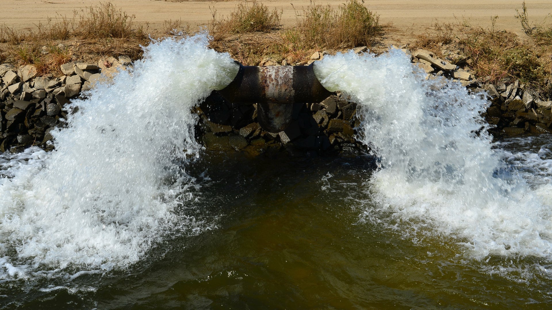 A massive industrial pipe spewing Shallowater’s premium, uranium-enriched tap water into a murky reservoir, because apparently, kidney health is just a suggestion.