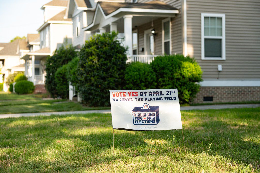 A political yard sign for "Virginians for Fair Elections" sits on a manicured lawn, ironically symbolizing the redistricting war Texas Republicans accidentally started and then lost.