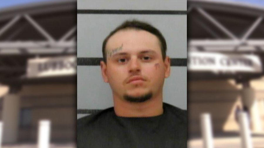 Mugshot of David Bowman with face tattoos, framed by a blurry background of the Lubbock County Detention Center entrance.