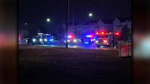 Emergency vehicles including police cars and a fire truck with flashing blue and red lights block a road at night near townhomes on North Quaker Avenue in Lubbock.