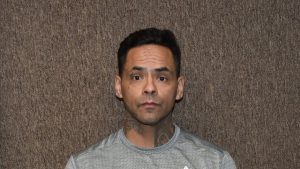 Mugshot of Andrew Robles looking directly at the camera against a textured brown background.