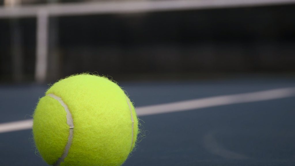 A close-up of a lone yellow tennis ball sitting on a blue court at the Burgess-Rushing Tennis Center in Lubbock.