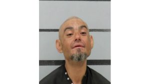 Mugshot of Jerry Smith looking upward with a graying goatee against a gray and black striped background.
