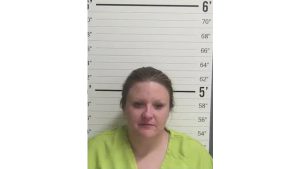 Mugshot of Ruby Outlaw in a lime green jumpsuit standing in front of a height chart during her booking in Curry County.