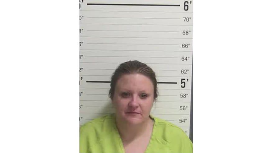 Mugshot of Ruby Outlaw in a lime green jumpsuit standing in front of a height chart during her booking in Curry County.