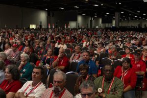 A large crowd of delegates sitting in rows of chairs inside a massive convention hall during the Texas Republican State Convention.