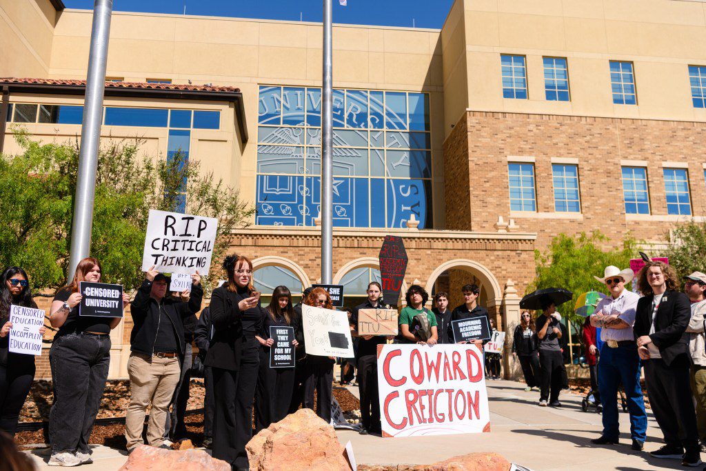 A group of students and faculty protesting outside a Texas Tech University System building, holding signs that read "R.I.P. Critical Thinking" and "Coward Creighton."