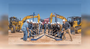 A group of corporate executives and local officials wearing white hard hats use ceremonial shovels during the groundbreaking event for the Aligned Data Centers Project Caprock campus in Abernathy, Texas, with large yellow excavators and an American flag visible in the background.