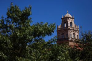 The Spanish Renaissance tower of the Texas Tech University Administration Building framed by tree branches in Lubbock, Texas.